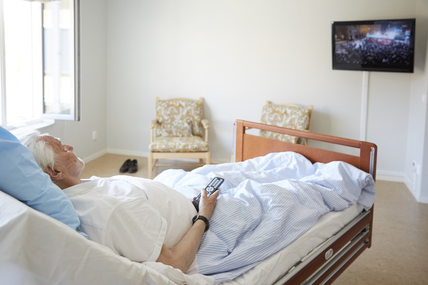 Senior man watching TV while reclining on bed